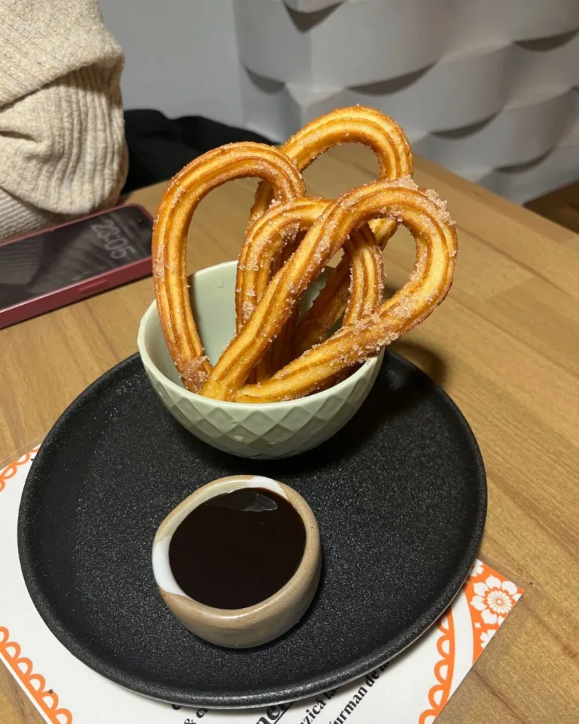 Churros cu sos de ciocolată pe farfurie neagră: poza de pe masa de lemn și varianta pe fundal gri deschis, înainte