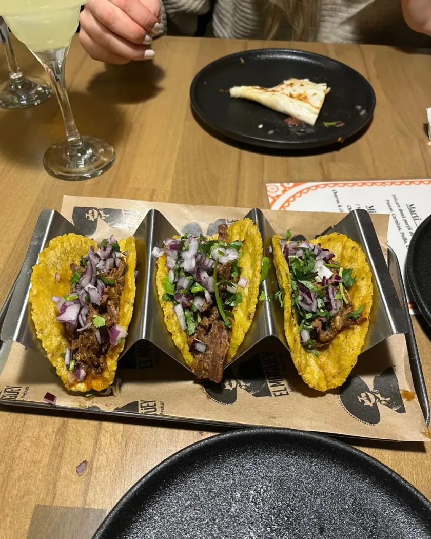 Trei tacos pe suport de lemn: poza de pe masă, cu pahare în jur, și varianta curată pentru meniu, înainte